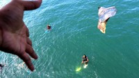Penumpang kapal melempar uang kepada anak logam di Pelabuhan Ketapang Banyuwangi, Jawa Timur, Rabu (19/4/2023). 