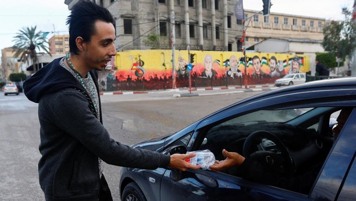 A Palestinian Christian man Ehab Ayyad offers dates and water to Muslims held up in traffic or getting late for home to break their fast during Ramadan, in Gaza City April 12, 2023. REUTERS/Ibraheem Abu Mustafa