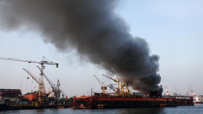 Petugas dengan menggunakan kapal tunda (tug boat) menyemprotkan air ke KM Anugerah Mandiri 8 yang terbakar di atas dok apung PT DOK dan Perkapalan Surabaya, Pelabuhan Tanjung Perak, Surabaya, Jawa Timur, Rabu (19/4/2023). Sejumlah unit kendaraan pemadam kebakaran dan kapal tunda (tug boat) dikerahkan untuk memadamkan kebakaran kapal kargo yang sedang dalam perbaikan tersebut. ANTARA FOTO/Didik Suhartono/YU