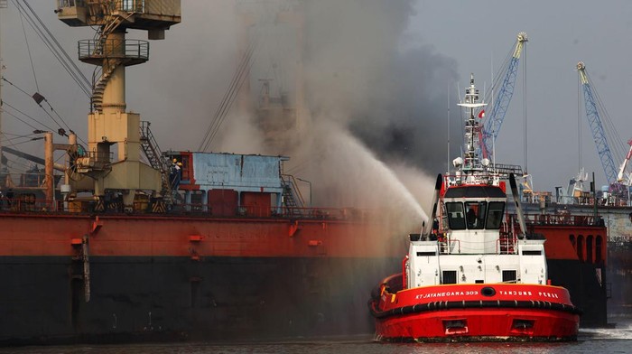 Petugas dengan menggunakan kapal tunda (tug boat) menyemprotkan air ke KM Anugerah Mandiri 8 yang terbakar di atas dok apung PT DOK dan Perkapalan Surabaya, Pelabuhan Tanjung Perak, Surabaya, Jawa Timur, Rabu (19/4/2023). Sejumlah unit kendaraan pemadam kebakaran dan kapal tunda (tug boat) dikerahkan untuk memadamkan kebakaran kapal kargo yang sedang dalam perbaikan tersebut. ANTARA FOTO/Didik Suhartono/YU
