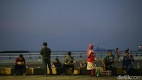 Pemudik nampak santai menunggu naik kapal dengan jajan di pedagang asongan yang keliling dermaga. 