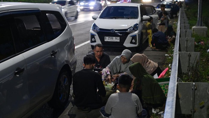 Sejumlah pemudik menyantap makanan saat berbuka puasa di badan jalan Tol Cikopo-Palimanan (Cipali), Majalengka, Jawa Barat, Rabu (19/4/2023). Meski berbahaya dan terlarang, sebagian pemudik nekat memanfaatkan badan jalan untuk tempat berbuka puasa karena 'rest area' terdekat telah penuh kapasitasnya dengan pemudik lain yang beristirahat. ANTARA FOTO/Aditya Pradana Putra/nym.