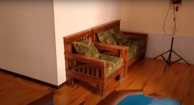 Bagian dalam rumahnya sendiri terlihat sederhana dan tak terlalu banyak dipenuhi barang. Di bagian sampingnya terdapat beberapa kursi kayu yang bisa digunakan untuk duduk-duduk dan mengobrol. Foto: YouTube/Abiza TV