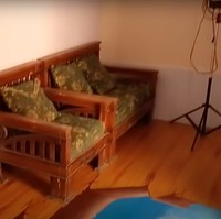 Bagian dalam rumahnya sendiri terlihat sederhana dan tak terlalu banyak dipenuhi barang. Di bagian sampingnya terdapat beberapa kursi kayu yang bisa digunakan untuk duduk-duduk dan mengobrol. Foto: YouTube/Abiza TV