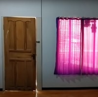Penampakan bagian dalam rumah menuju ke luar juga terlihat sederhana. Pintu rumah tampak terbuat dari kayu dan gorden jendelanya pun tampak simpel berwarna merah muda. Foto: YouTube/Abiza TV