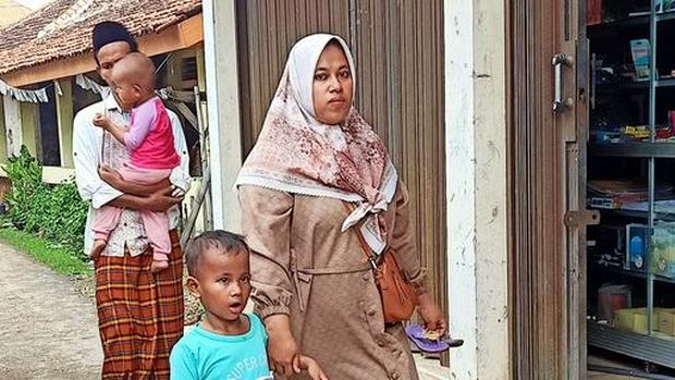 West Java, Indonesia – October 09, 2022: a moslem family is walking in a village alley