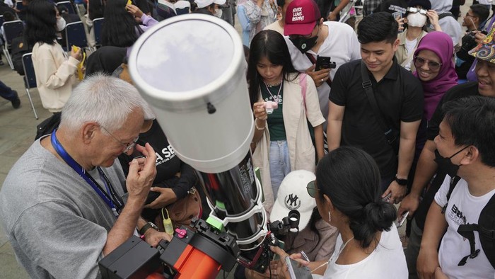 People use protective glasses to watch solar eclipse in Jakarta, Indonesia, Thursday, April 20, 2023. A rare solar eclipse will cross over remote parts of Australia, Indonesia and East Timor on Thursday. (AP Photo/Tatan Syuflana)
