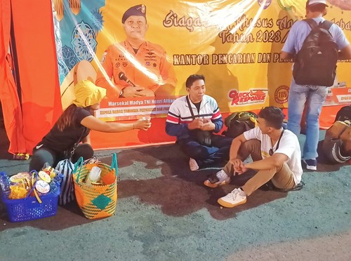 Ni Ketut Kariati saat melayani pemudik yang hendak membeli kopi saat antre di Pelabuhan Padangbai Kamis (20/4/2023) (foto: I Wayan Selamat Juniasa)