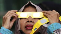 Warga melihat gerhana matahari hibrida menggunakan kacamata khusus.