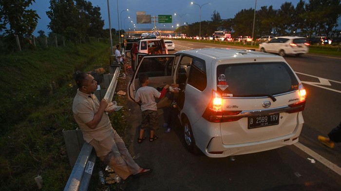 Sejumlah pemudik menyantap makanan saat berbuka puasa di badan jalan Tol Cikopo-Palimanan (Cipali), Majalengka, Jawa Barat, Rabu (19/4/2023). Meski berbahaya dan terlarang, sebagian pemudik nekat memanfaatkan badan jalan untuk tempat berbuka puasa karena rest area terdekat telah penuh kapasitasnya dengan pemudik lain yang beristirahat. ANTARA FOTO/Aditya Pradana Putra/nym.