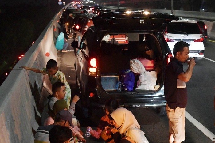 Sejumlah pemudik menyantap makanan saat berbuka puasa di badan jalan Tol Cikopo-Palimanan (Cipali), Majalengka, Jawa Barat, Rabu (19/4/2023). Meski berbahaya dan terlarang, sebagian pemudik nekat memanfaatkan badan jalan untuk tempat berbuka puasa karena rest area terdekat telah penuh kapasitasnya dengan pemudik lain yang beristirahat. ANTARA FOTO/Aditya Pradana Putra/nym.