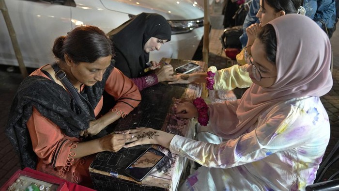Beauticians paint hands of customers with traditional henna in preparation for the upcoming Eid al-Fitr celebrations, in Lahore, Pakistan, Wednesday, April 19, 2023. Eid al-Fitr marks the end of the Islamic holy month of Ramadan. (AP Photo/K.M. Chaudary)