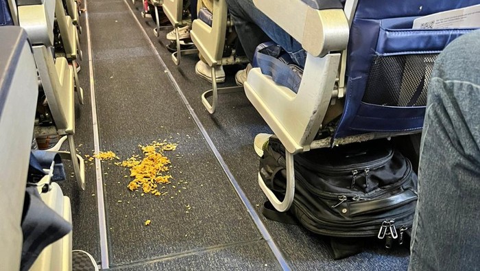 Nasi kuning tumpah bikin lantai pesawat kotor.
