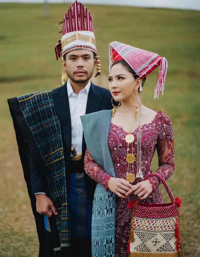 Yakup Hasibuan tampil gagah dalam balutan jas hitam dan kemeja yang dikombinasikan kain tenun dan selendang sebagai aksen. Dia juga memakai hiasan kepala tradisional Batak. Foto: Instagram/@jscmila