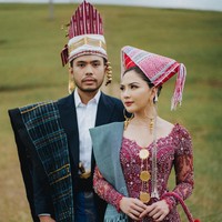 Yakup Hasibuan tampil gagah dalam balutan jas hitam dan kemeja yang dikombinasikan kain tenun dan selendang sebagai aksen. Dia juga memakai hiasan kepala tradisional Batak. Foto: Instagram/@jscmila