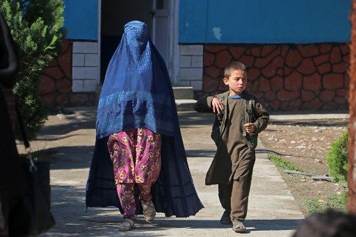 An Afghan woman walks along with a boy through a pathway in Fayzabad district of Badakhshan province on March 21, 2023. (Photo by OMER ABRAR / AFP)