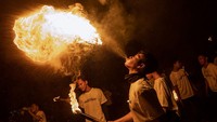 Seorang pria menyemburkan minyak ke obor yang menyala dan membuat kepulan api di udara saat parade menyambut Lebaran.