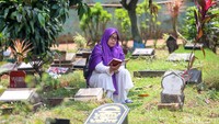 Seorang warga berdoa di depan makam keluarganya.