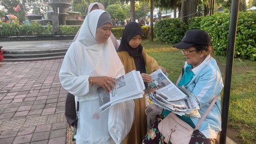 Nyoman Sindri saat melayani pembeli yang ingin membeli koran bekasnya di Lapangan Ngurah Rai, Taman Kota Singaraja, Buleleng, Sabtu (22/4/2023). (Made Wijaya Kusuma/detikBali)