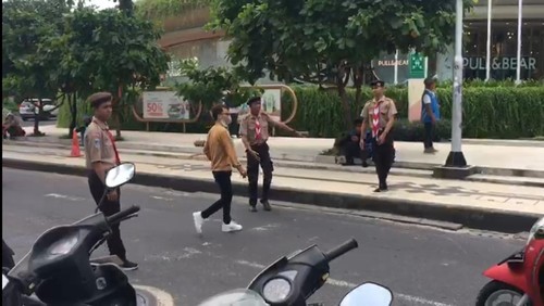 Pramuka membantu polisi dalam pengaturan arus lalu lintas di depan Pantai Kuta, Jumat (21/4/2023).