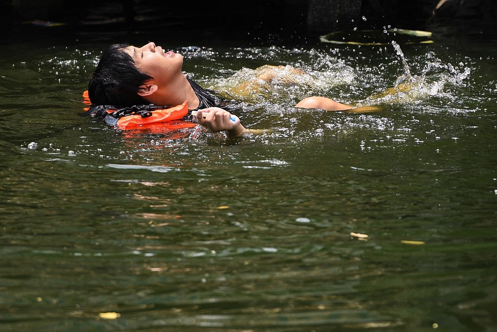 Seorang pria berenang di kanal saat suhu mencapai rekor 45,4 derajat Celcius (113,7 Fahrenheit) di Bangkok, Thailand, 22 April 2023. (REUTERS/Chalinee Thirasupa)