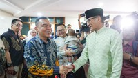 Sandiaga dan Dasco tampak bersalaman. Sandiaga yang mengenakan baju koko hijau terlihat tersenyum.