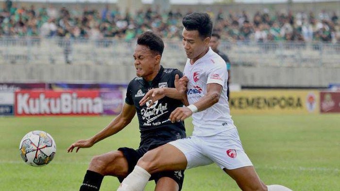 Bek PSM Makassar Agung Mannan menghalau pergerakan pemain Persebaya Surabaya.