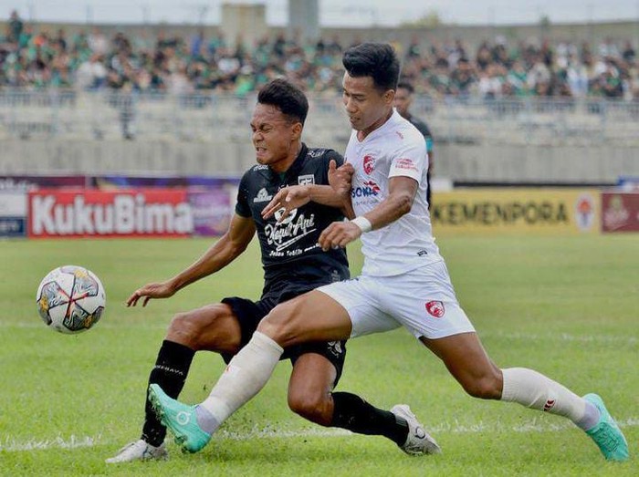Bek PSM Makassar Agung Mannan menghalau pergerakan pemain Persebaya Surabaya.