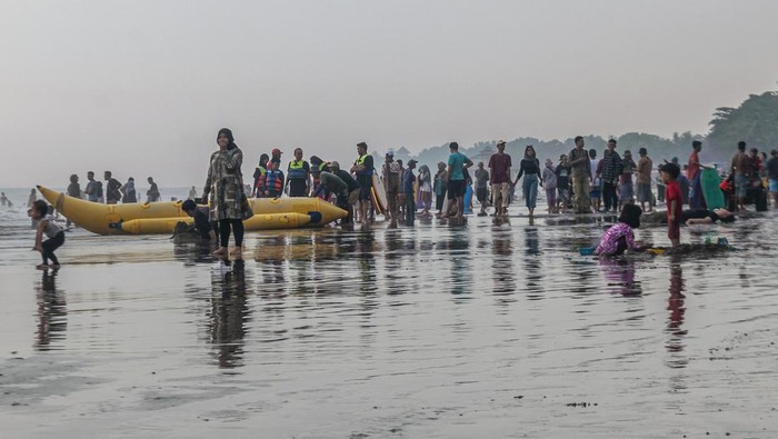 Dua anak bermain pasir di Pantai Anyer, Kabupaten Serang, Banten, Minggu (23/4/2023). Objek wisata pantai yang menjadi salah satu destinasi wisata warga Banten dan Jakarta tersebut ramai dikunjungi wisatawan pada hari kedua Lebaran 1444 H. ANTARA FOTO/Muhammad Bagus Khoirunas/nym.