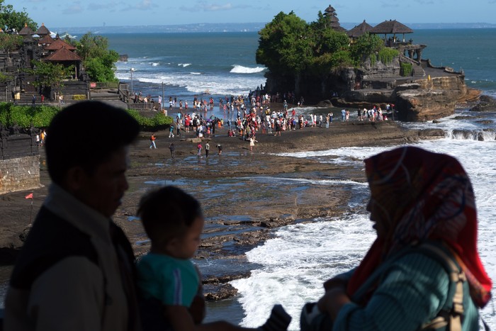 Wisatawan menikmati suasana pantai saat berkunjung di objek wisata Tanah Lot, Tabanan, Bali, Minggu (23/4/2023). Pengelola Daya Tarik Wisata (DTW) Tanah Lot mencatat jumlah kunjungan wisatawan saat hari libur Idul Fitri 1444 H pada Sabtu (22/4) sebanyak 9.202 orang, angka tersebut meningkat dibandingkan jumlah kunjungan pada hari-hari biasa yang rata-rata 2.000 orang. ANTARA FOTO/Nyoman Hendra Wibowo/nym.