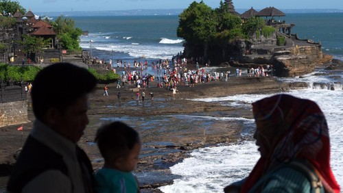 Wisatawan menikmati suasana pantai saat berkunjung di objek wisata Tanah Lot, Tabanan, Bali, Minggu (23/4/2023). Pengelola Daya Tarik Wisata (DTW) Tanah Lot mencatat jumlah kunjungan wisatawan saat hari libur Idul Fitri 1444 H pada Sabtu (22/4) sebanyak 9.202 orang, angka tersebut meningkat dibandingkan jumlah kunjungan pada hari-hari biasa yang rata-rata 2.000 orang. ANTARA FOTO/Nyoman Hendra Wibowo/nym.