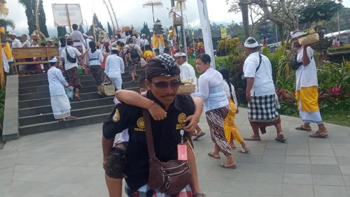 Pecalang menggendong pemedek yang pingsan di Pura Agung Besakih Senin (24/4/2023) Foto: Istimewa