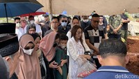 Andiez (memakai jilbab pink) terlihat memeluk anak semata wayangnya saat menyaksikan jenazah Iqbal Pakula dimasukan ke dalam liang lahat. Foto: Pingkan/detikHOT