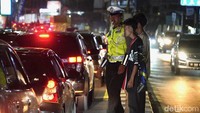 Foto: Polisi membantu warga yang hendak menyeberang di Jalan Poros Maros-Makassar, Sulsel yang tengah macet di tengah puncak arus balik lebaran. (Agung Pramono/detikSulsel)