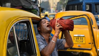 Pengemudi taksi di Kolkata, India, meminum air agar tidak dehidrasi di tengah teriknya Matahari siang hari. Foto: Getty Images