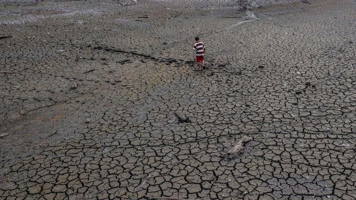 TOPSHOT - Aerial view showing a boy walking in the dried bed of Alhajuela Lake during the summer drought, in the Colon province, 50 km north of Panama City, on April 21, 2023. - The scarcity of rainfall due to global warming has forced the Panama Canal to reduce the draft of ships passing through the interoceanic waterway, in the midst of a water supply crisis that threatens the future of this maritime route. The Alhajuela lake, in the Colon province, 50 km north of Panama City, is one of the main lakes that supplies water to the locks of the Panama Canal and is at its lowest level of recent years. (Photo by Luis ACOSTA / AFP) (Photo by LUIS ACOSTA/AFP via Getty Images)