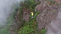 Seorang pria berjalan melintasi lembah dengan seutas tali di Taman Geologi Nasional Shiniuzhai, Yueyang, China, Senin (24/4/2023).