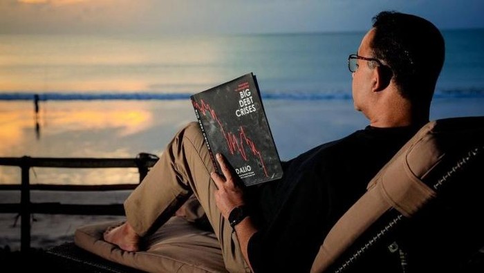 Anies Baswedan unggah foto baca buku di pinggir laut.