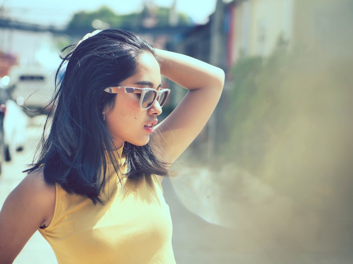 Happy Asian woman wearing sunglasses with sun light outdoor, lifestyle concept.  Reflection effect.