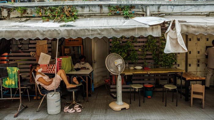 Residents rest in front of a fan in Bangkok, Thailand, on Tuesday, April 25, 2023. Thailands government will cut power rates ahead of next months general election, in an effort to ease the plight of consumers and businesses grappling with sweltering temperatures. Photographer: Andre Malerba/Bloomberg via Getty Images