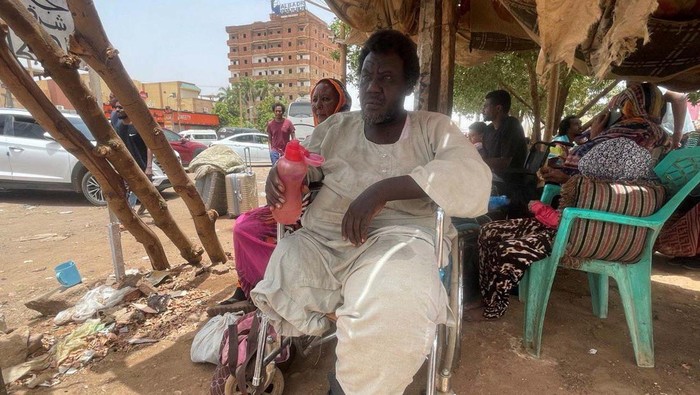 A woman is helped to drink water as she flees clashes between the paramilitary Rapid Support Forces and the army in Khartoum, Sudan April 25, 2023. REUTERS/El-Tayeb Siddig