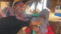 Warga memberi minum pengungsi yang kelelahan.