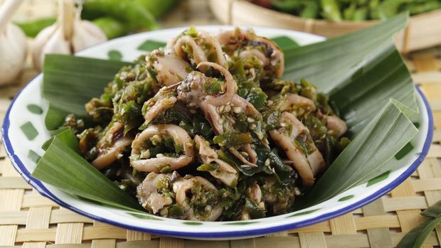 Close Up Cumi Cabe Ijo, Spicy Stir Fry Squid with Green Pepper, Shallot, and Garlic. Served on Enamel Plate on Wooden Table