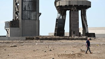 Seorang warga berjalan melalui puing-puing di landasan peluncuran pada 22 April 2023, setelah SpaceX Starship lepas landas pada 20 April untuk uji terbang dari Starbase di Boca Chica, Texas. Peluncuran itu memicu bongkahan beton pecah dan beterbangan di landasan, logam bengkok, hingga terbentuknya kawah di dalam tanah. Foto: AFP via Getty Images/PATRICK T. FALLON