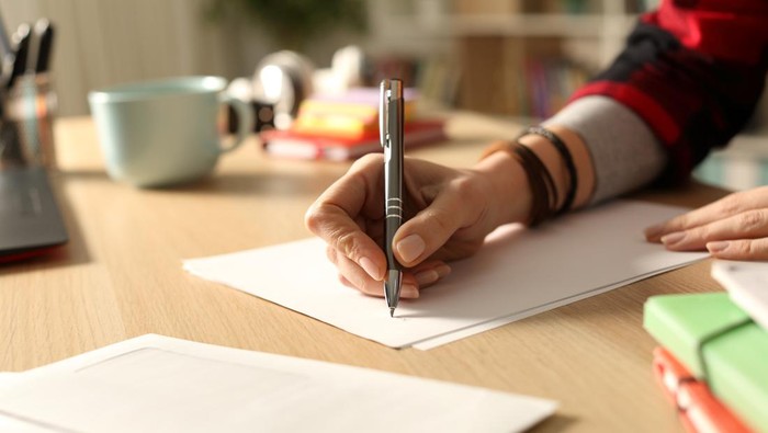 Student hand writing letter at home in the night