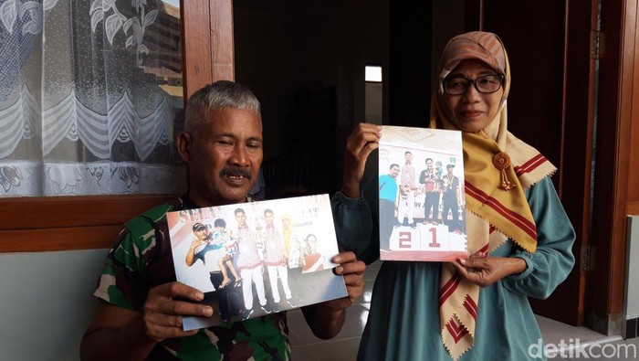 Kedua orang tua menunjukkan foto Yoga saat menjadi juara, Kamis (27/4/2023).