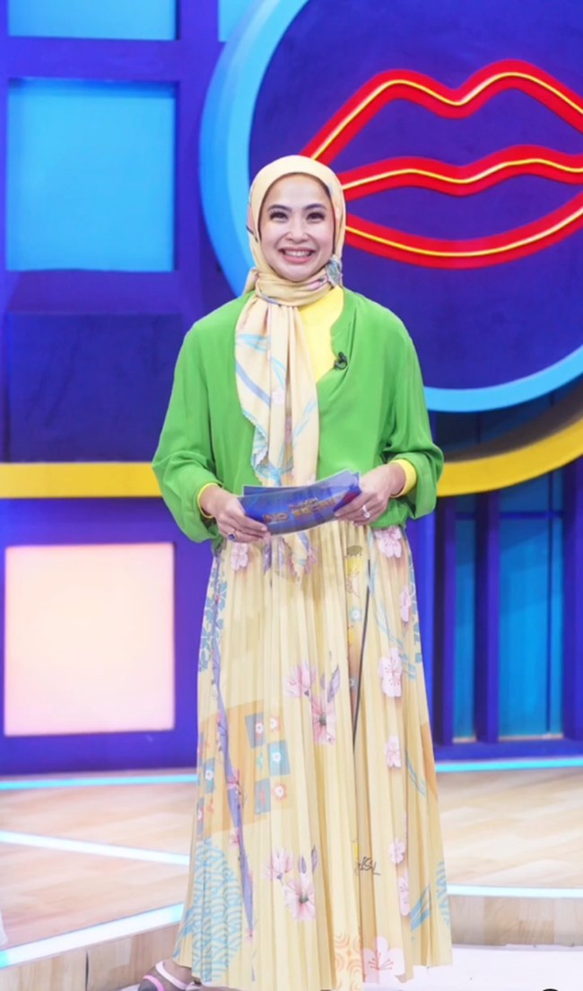 Wanita kelahiran 1 November 1973 juga mencoba hijab segi empat motif ketika membawakan acara Rumpi. Feni mengenakan hijab segi empat motif warna kuning, dipadu dengan kemeja warna hijau dan rok plisket warna senada.  Foto: Dok. Instagram @fenirose.