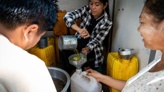 YANGON, MYANMAR - APRIL 4: People line up to receive low-cost or free cooking oil from a charity sponsor on the street as the daily life continues in Yangon, Mynmar on April 4, 2023. On Feb.01, 2021, the military junta government (Tatmadaw) seized power by coup and jailed the democratically-elected National League for Democracy (NLD) government and plunged the country into an ongoing humanitarian crisis, described by many as a civil war or the People's Uprising. (Photo by Matt Hunt/Anadolu Agency via Getty Images)