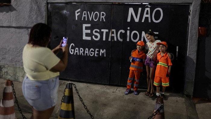 Keren, 2 Bocah Ini Jadi Pasukan Oranye di Brasil 6-year-old Bryan Mota de Oliveira, wearing an orange uniform similar to the cleaning company Comlurbβs uniform, throws garbage into a truck as he and his brother Bernardo volunteer to help cleaning workers with garbage collection, an initiative they came up with spurred by their interest in the garbage truck, in Bangu neighborhood, Rio de Janeiro, Brazil April 26, 2023. REUTERS/Pilar Olivares