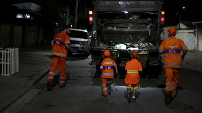 Keren, 2 Bocah Ini Jadi Pasukan Oranye di Brasil 6-year-old Bryan Mota de Oliveira, wearing an orange uniform similar to the cleaning company Comlurbβs uniform, throws garbage into a truck as he and his brother Bernardo volunteer to help cleaning workers with garbage collection, an initiative they came up with spurred by their interest in the garbage truck, in Bangu neighborhood, Rio de Janeiro, Brazil April 26, 2023. REUTERS/Pilar Olivares